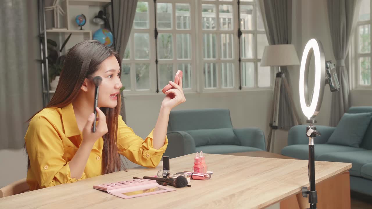 Asia Beauty Blogger Woman Make-Up With Cosmetic Powder Brush At Home Studio, Recording Video On Smartphone