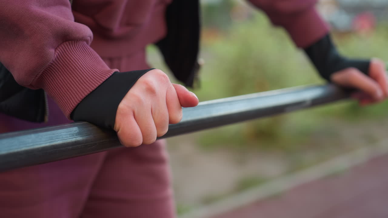 Close up view of fitness instructor hands resting on exercise bar outdoors, focusing on strength and determination in training, highlighting a calm moment between intense workout sessions
