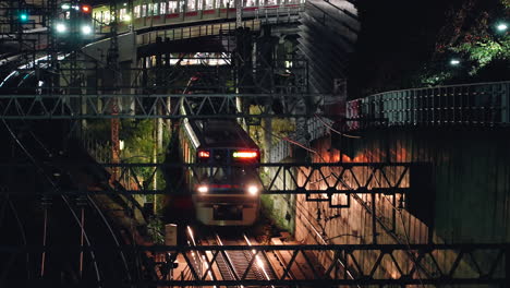 trains on railway track with headlights on at night in city of tokyo, japan