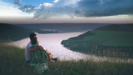 the man covering his woman with a plaid on the rainy sky background