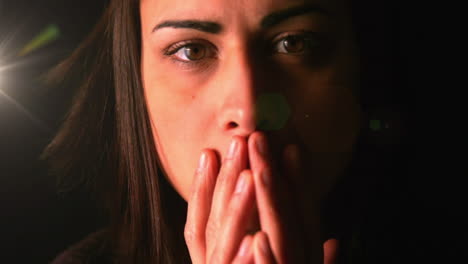 close up view of stressed caucasian woman against spot of light on black background