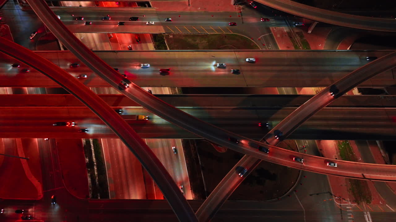 Lively traffic on the motorways and trestles in the modern intersection. Multi-level interchange at night from aerial view
