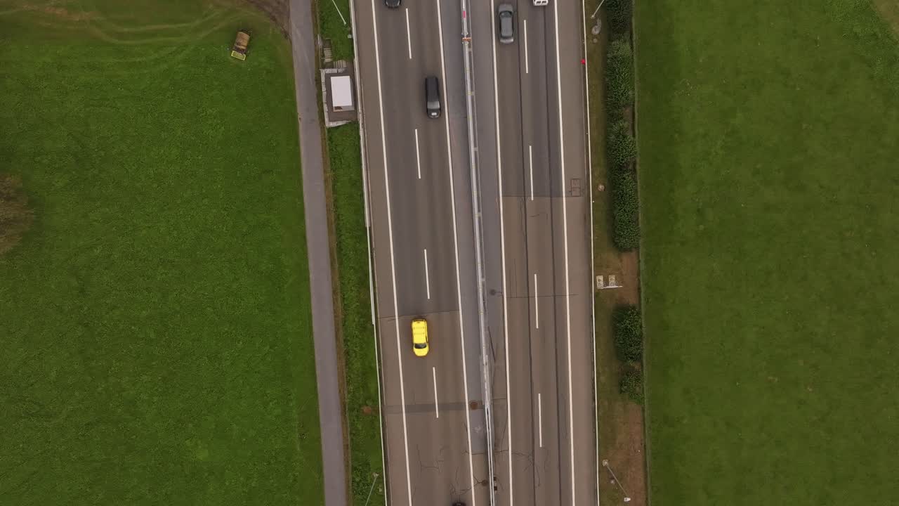 Cinematic hyperlapse drone motion over a highway in Switzerland, surrounded by beautiful green fields.