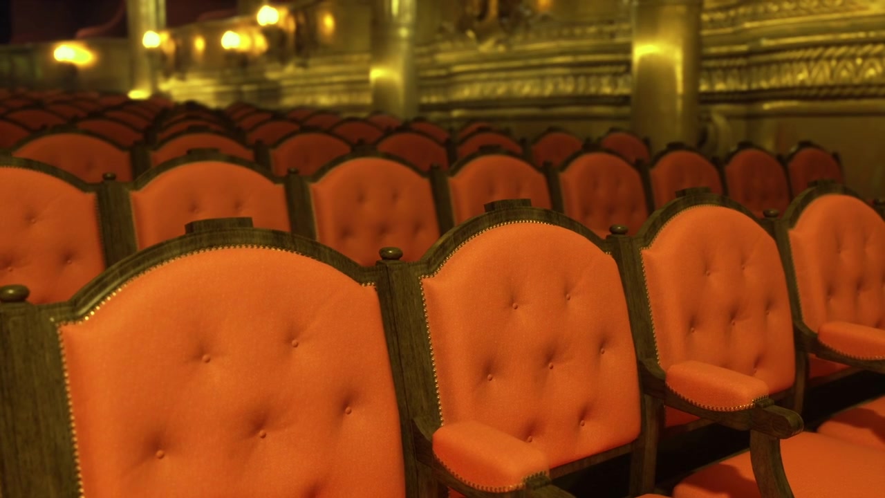Silenziose poltrone di velluto sotto lampadari scintillanti che creano un'atmosfera teatrale nostalgica