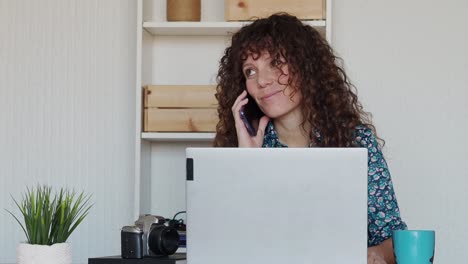 mujer alegre hablando en teléfono inteligente y trabajando desde casa