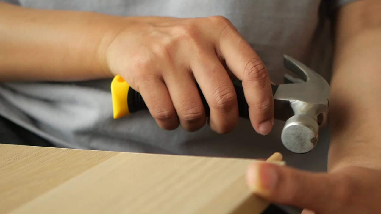 Person Using a Hammer to Assemble Wood