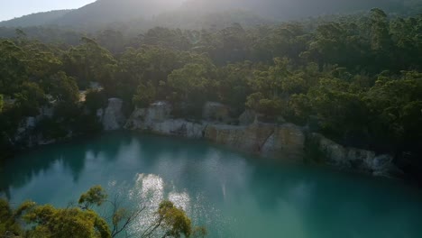 Backward-drone-view-of-a-beautiful-little-blue-lake-in-Tasmania,-Australia