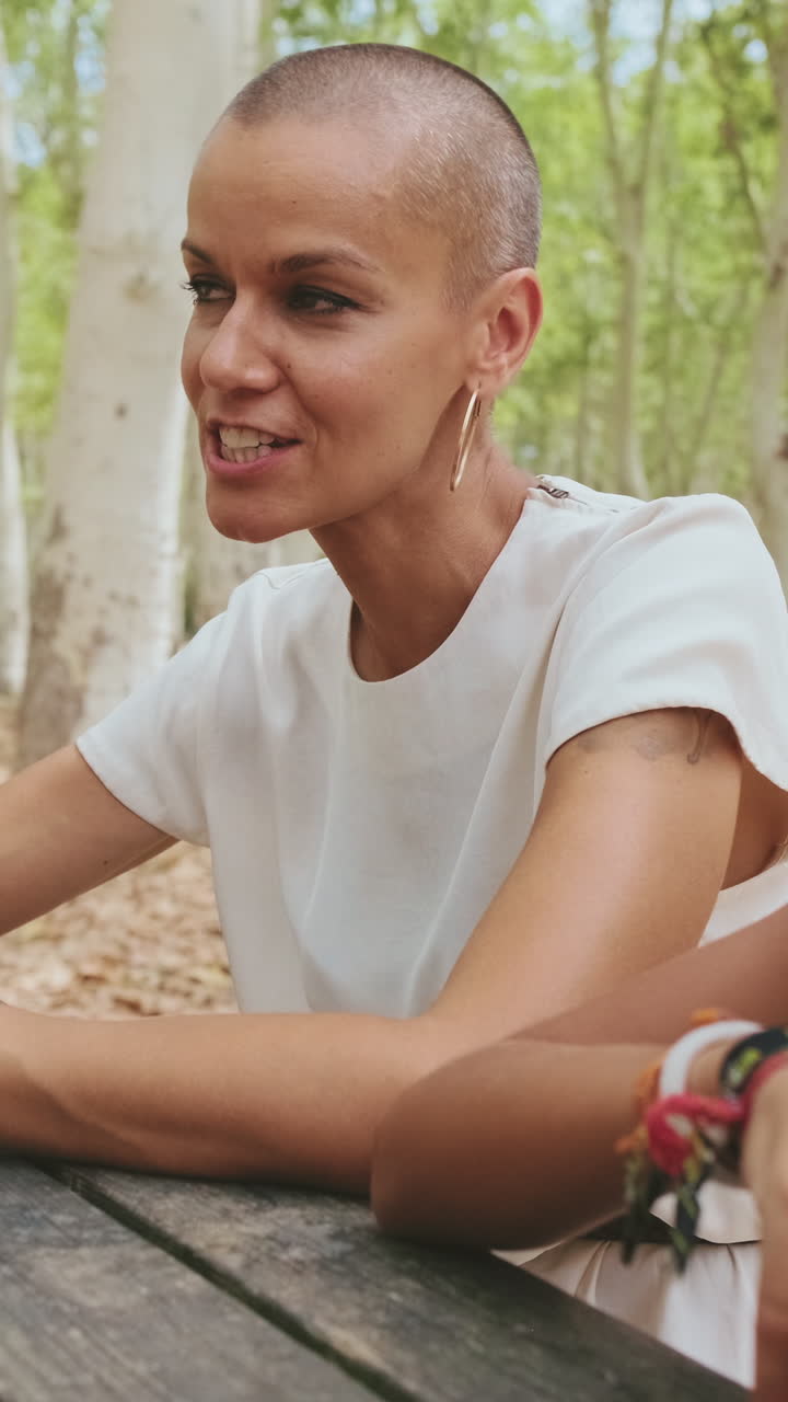 Donna felice con la testa rasata che sorride e parla in un parco