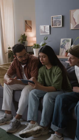 three friends socializing and looking at a smartphone together on a couch