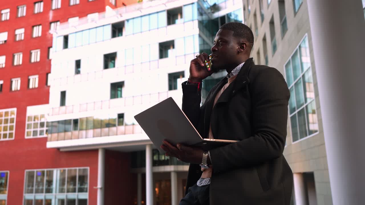 Uomo che usa telefono e laptop in ambiente urbano