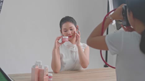 behind the scenes on photo shoot: beautiful asian model poses for a photographer, she takes photos with professional camera