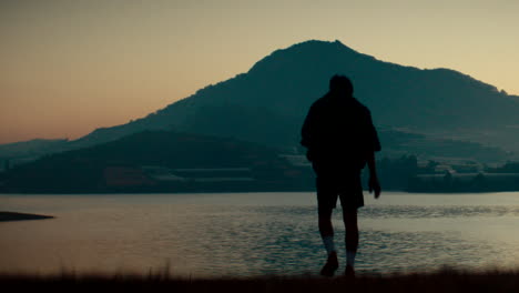 man contemplating sunrise over a lake