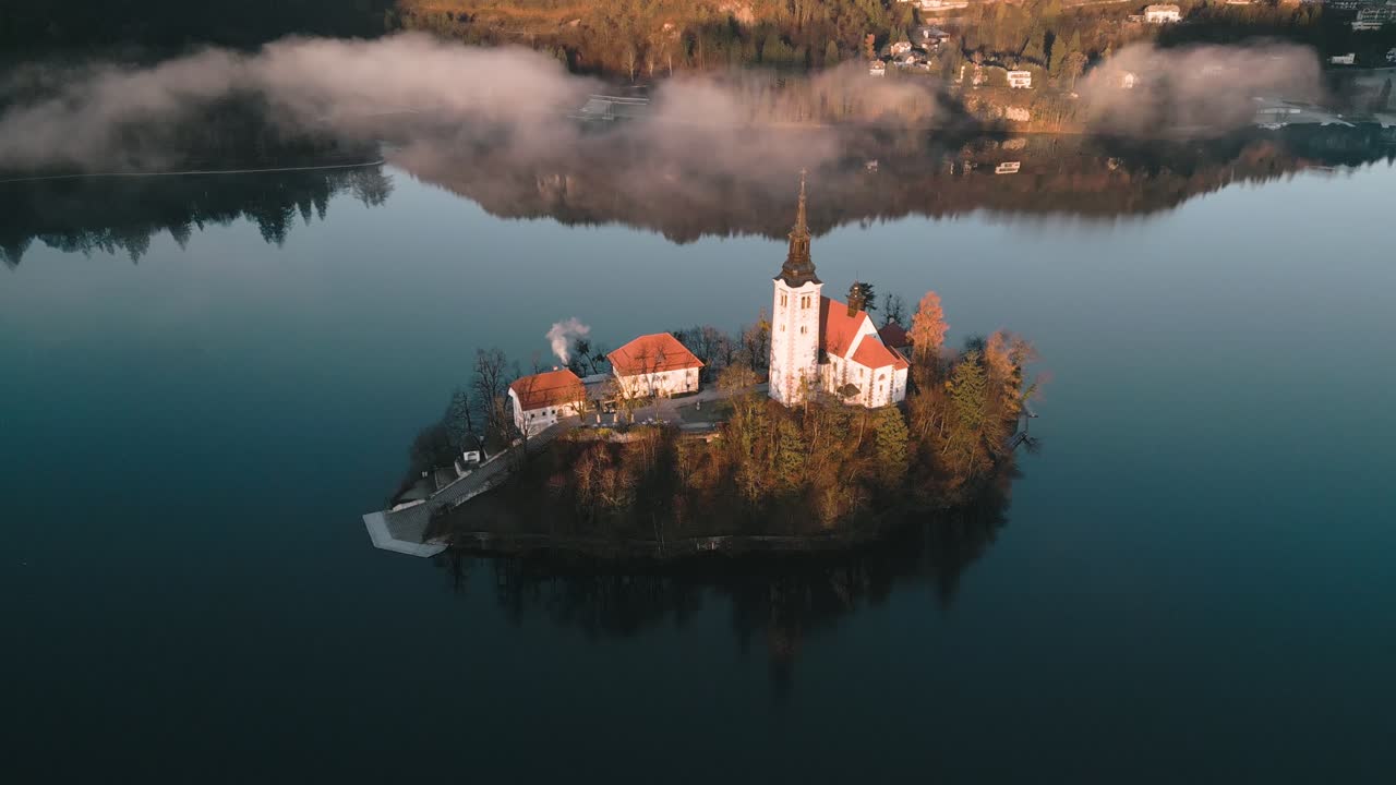 In alto sopra le nuvole, il filmato aereo cinematografico inquadra l'iconica isola della chiesa nel Lago di Bled, Slovenia, nell'Europa Centrale