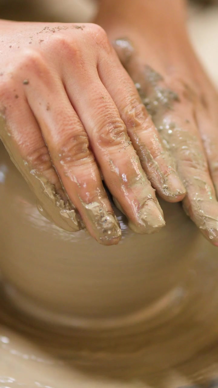 Primo piano delle mani di un vasaio che modellano argilla umida in un recipiente a Nonthaburi, Thailandia