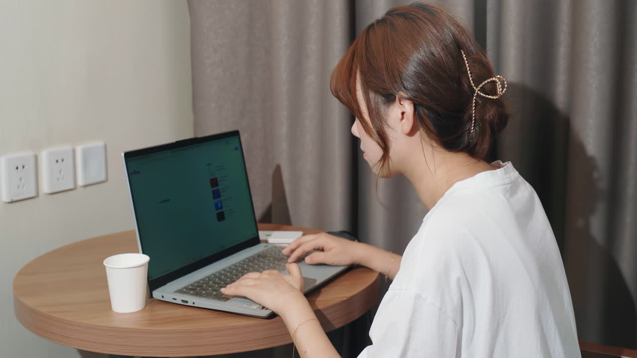 매력적인 젊은 소녀들이 집에서 소파에 앉아 인터넷을 서핑하거나 노트북 컴퓨터에서 온라인 쇼핑하고 있습니다.