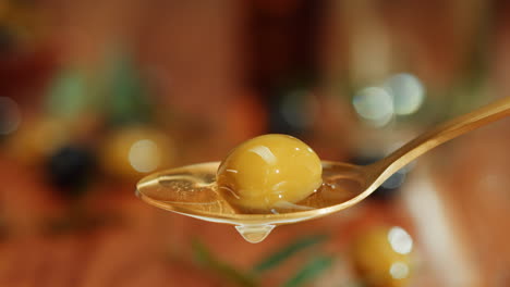 green olive on a golden spoon