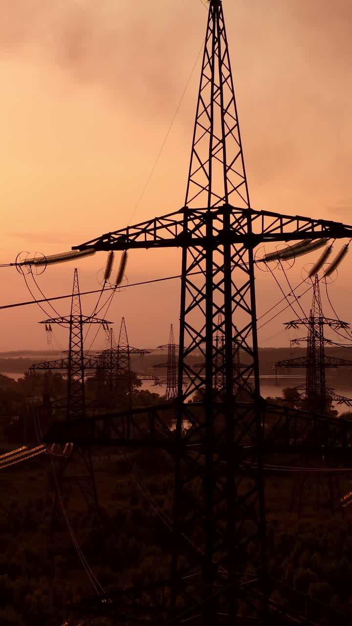 Technogenic landscape, urban. The energy of the pole in the rays of the rising sun. Posts for the transfer of high lead. Steel electric pillars concept. Vertical video