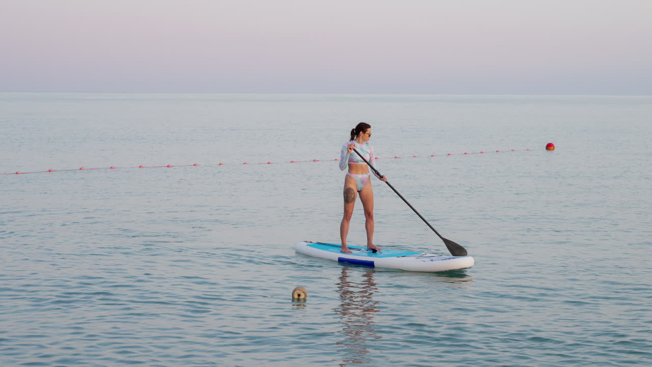 mujer haciendo paddleboard en el océano al atardecer