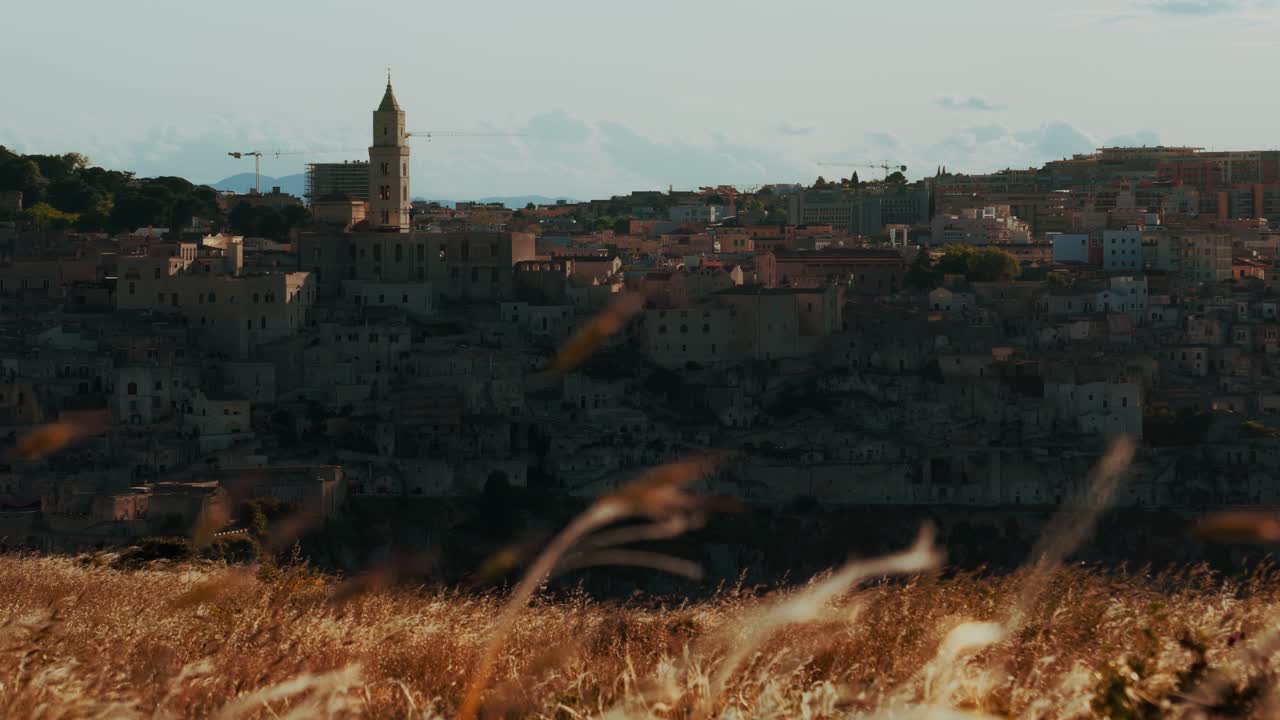 Matera, Italia. Los históricos Sassi vistos desde los campos dorados a la cálida luz del sol al final de la tarde en Basilicata.