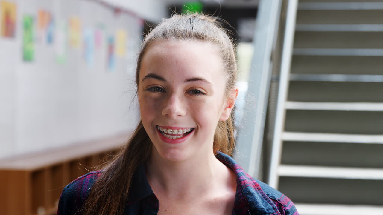 Portrait Of Female High School Student Standing By Stairs In College Building