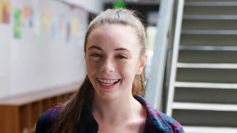 portrait of female high school student standing by stairs in college building