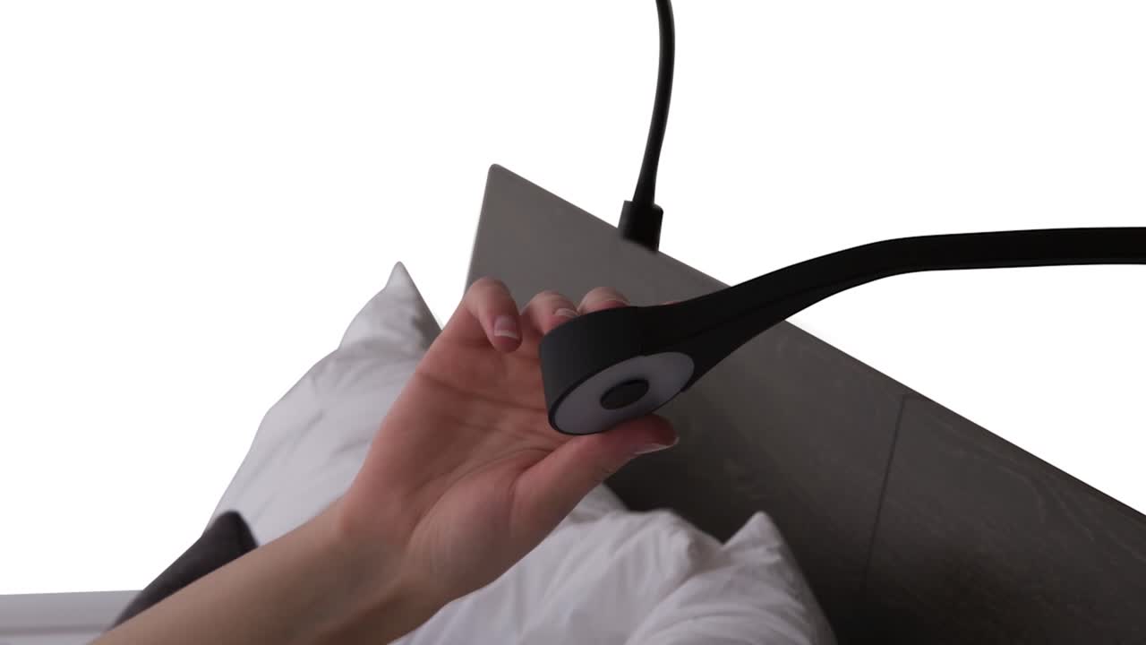 A young woman's hand turns a pressure touch sensor USB LED bed frame reading light on and off