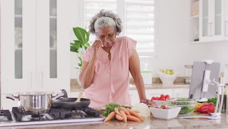 Portrait-of-happy-senior-african-american-woman-cooking-in-kitchen