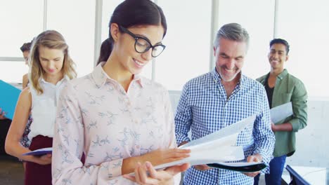 Smiling-business-executives-standing-with-file-in-office-4k