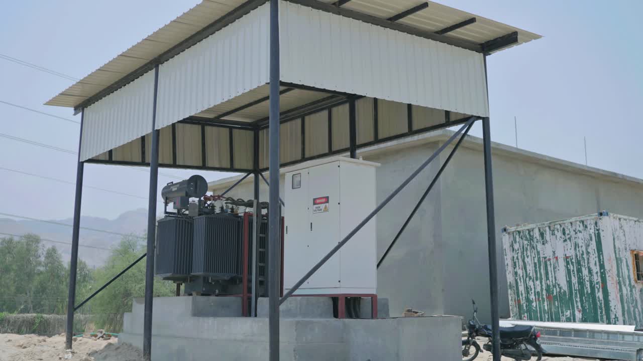 Profile view of a electrical transformer beneath a shed