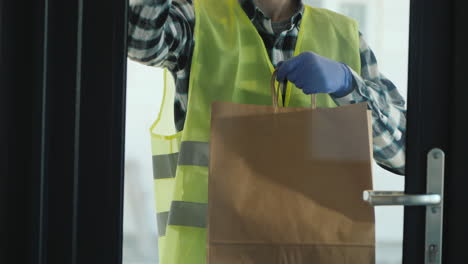 the male courier brings a package of groceries to the order door