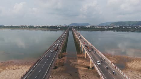 this aerial video captures the city's bustling urban landscape, where the majestic krishna river flows beneath the intersecting chennai-kolkata highway bridge, bustling with vehicular traffic