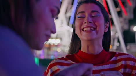 closeup girl talking friend at colorful ferris wheel. positive female hang out
