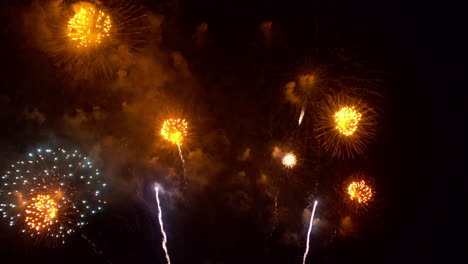 destellos de naranja y azul iluminan la oscuridad mientras el espectáculo de fuegos artificiales llena el cielo