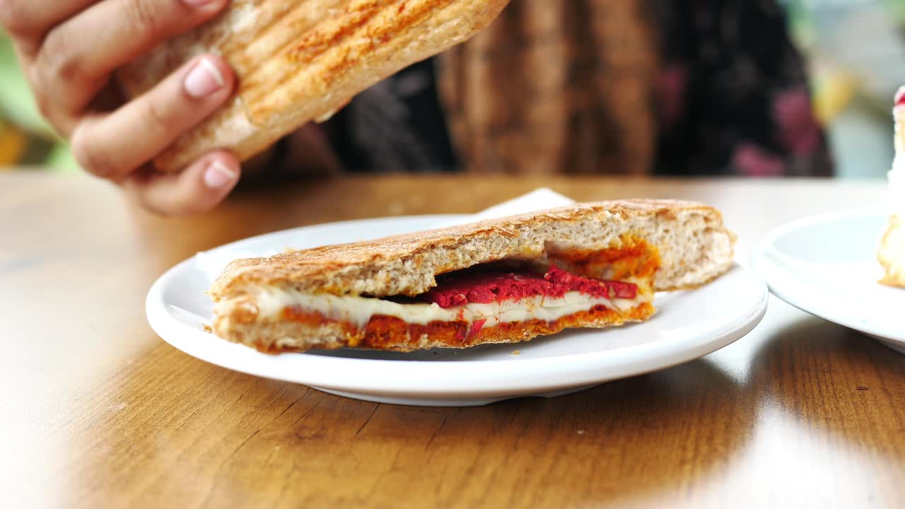 persona comiendo un sándwich a la parrilla