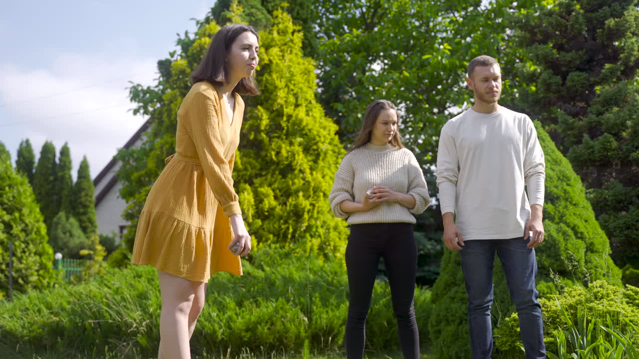 晴れた日に公園でペタンクボールを投げる白人の若い女性の側面図