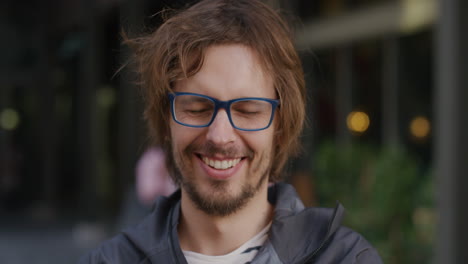 portrait cute young hipster man laughing enjoying relaxed urban lifestyle happy caucasian geek wearing glasses in city slow motion