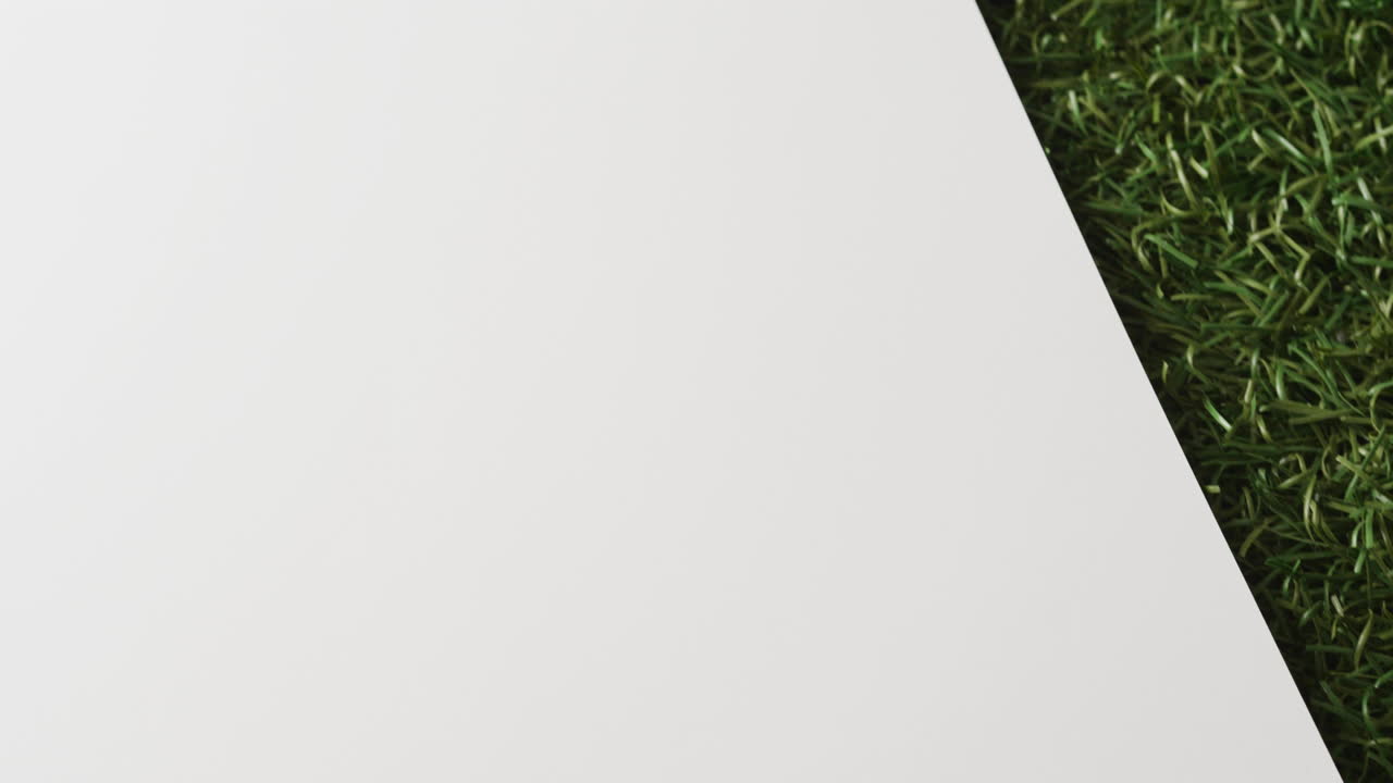 Close up of golf ball on grass with white background, copy space, slow motion