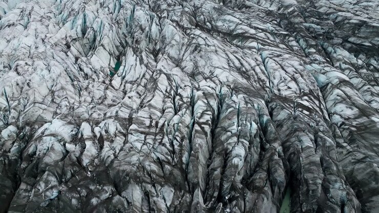 Ice terraces of glacier tongue, rough surface with crack pattern, aerial view