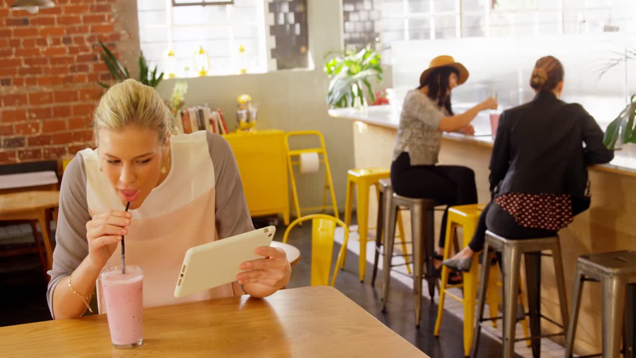 mujer ejecutiva tomando un batido mientras usa una tableta digital 4k