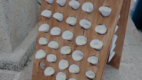 wooden display board holding paper cones filled with petals, set up for an outdoor event.
