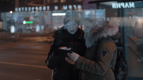 two women with pad in evening city street