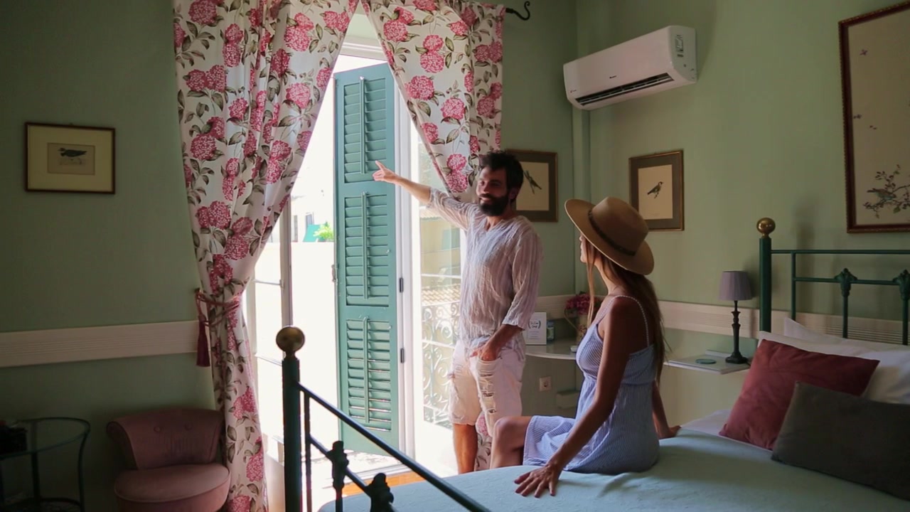 Young Tourists in Summer Outfits Adoring the Balcony View from a Charming Greek Guest House Room