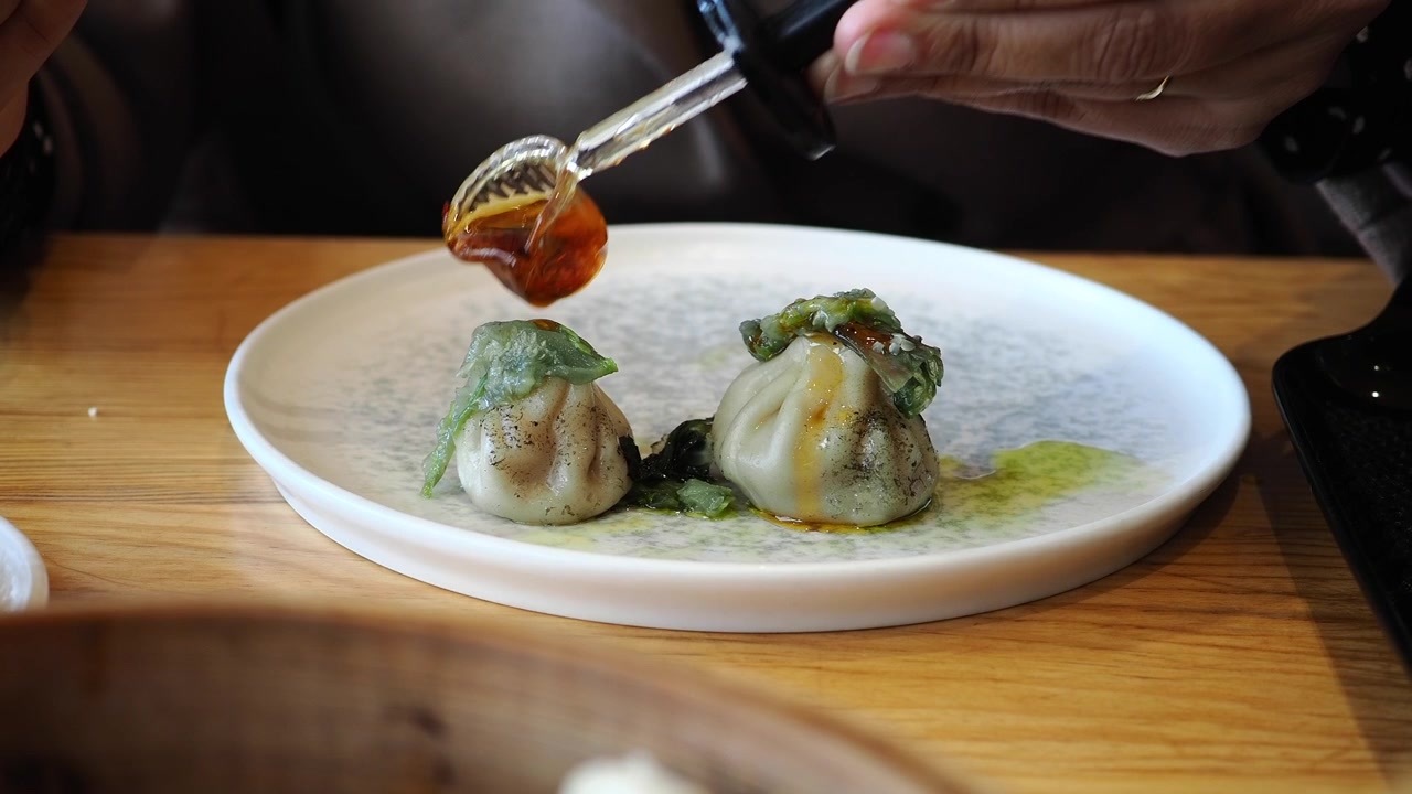 Adding Chili Oil to Gourmet Dumplings on a White Plate