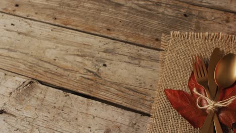 video of cutlery, cloth and autumn decoration lying on wooden surface