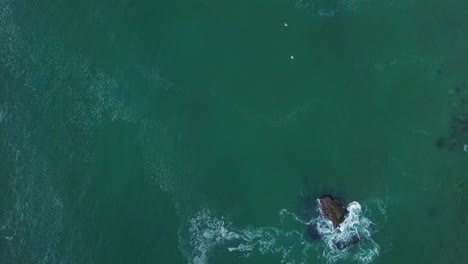 Bedruthan-Steps-Sea-Stack-At-High-Tide---Cornwall,-UK---aerial-top-down,-slow-motion