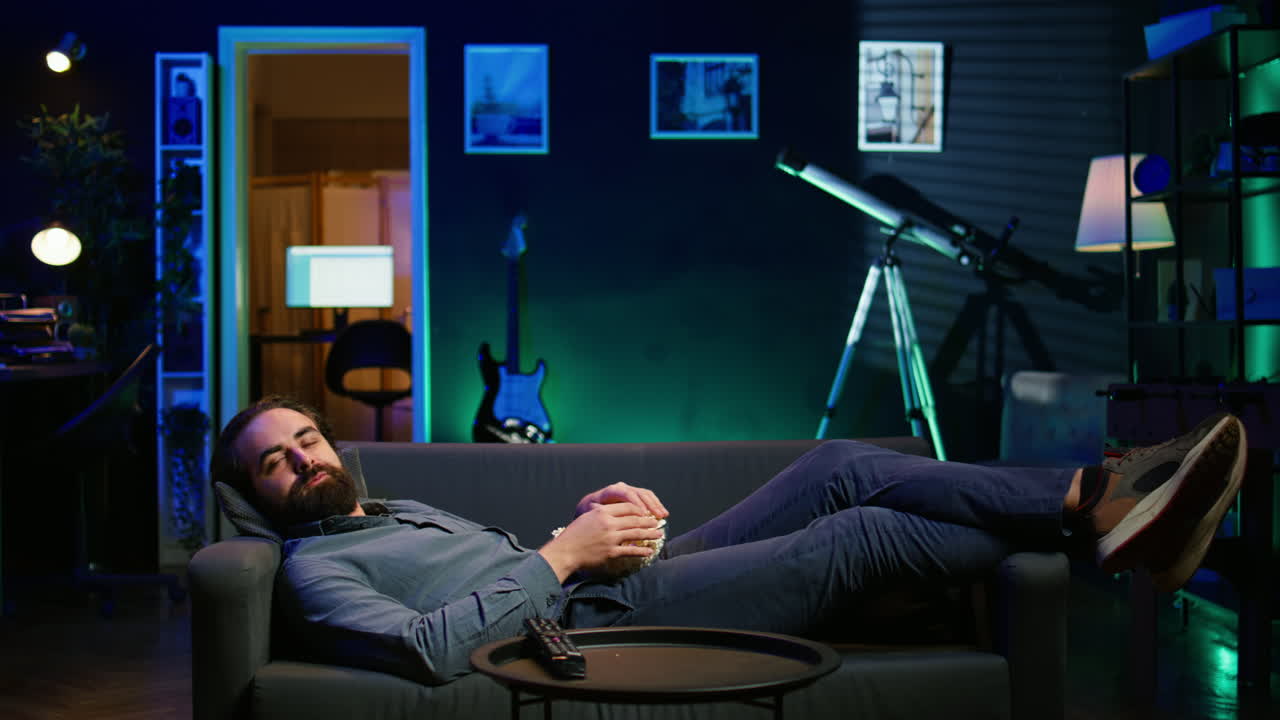 영화 를 보는 동안 소파 에 누워서 팝콘 을 먹는 미소 짓는 남자