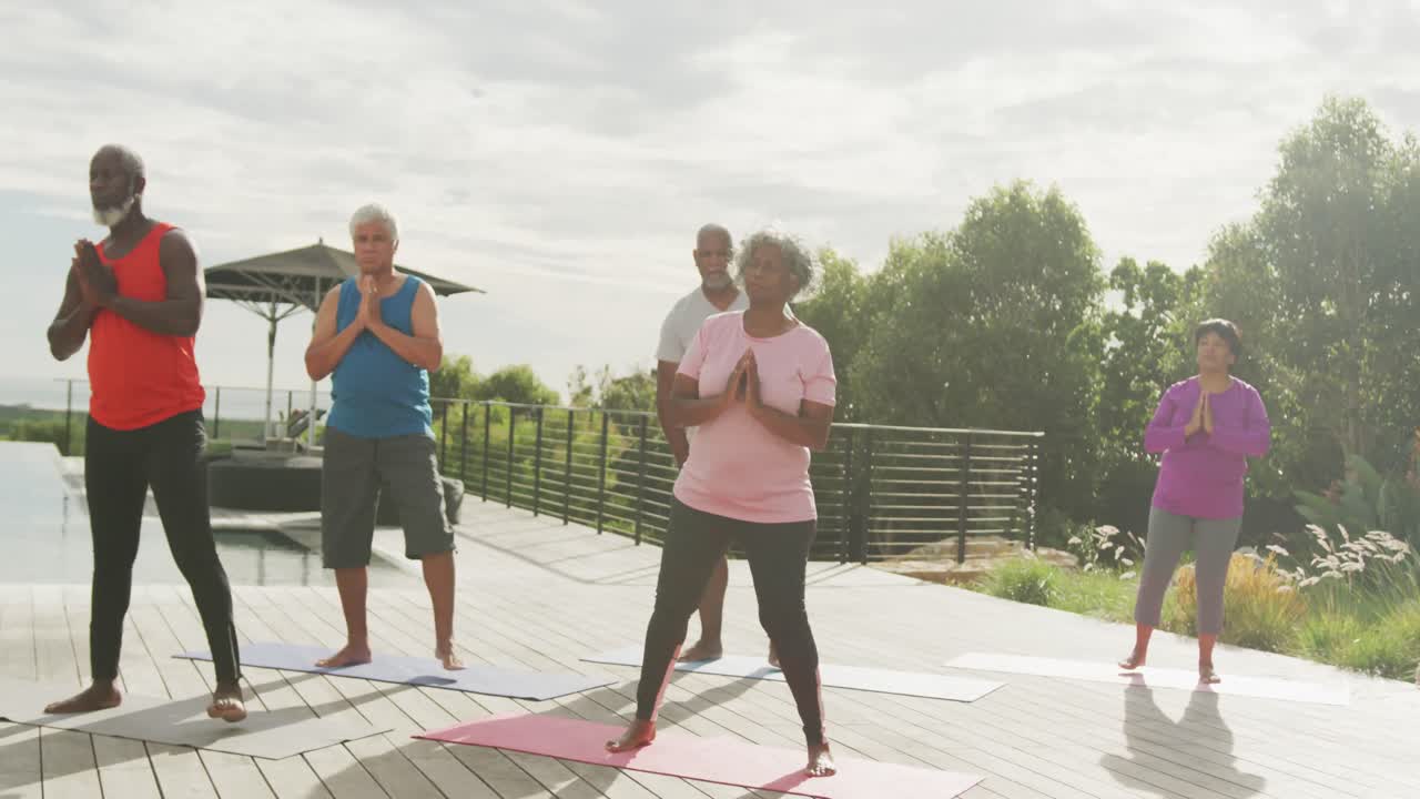 Anziani di diverse provenienze che praticano yoga in giardino in una casa di riposo.