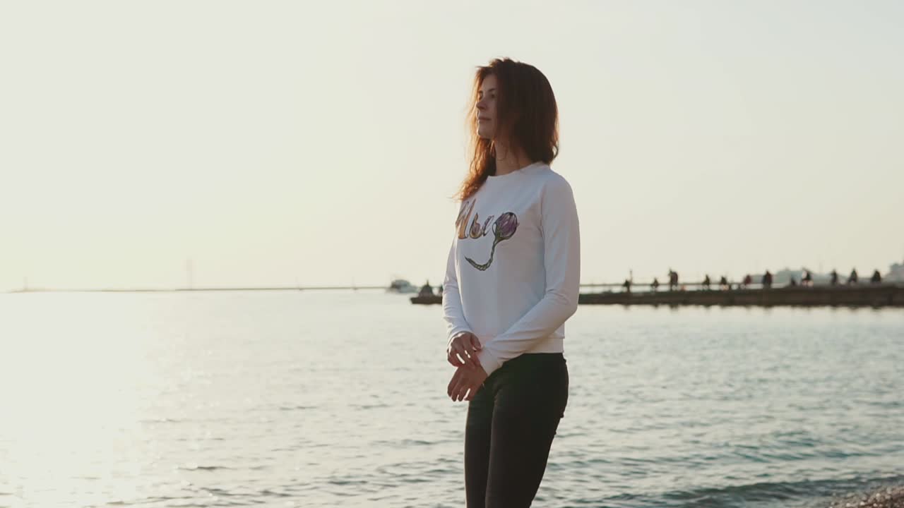 Kvinde går på stranden ved solnedgang
