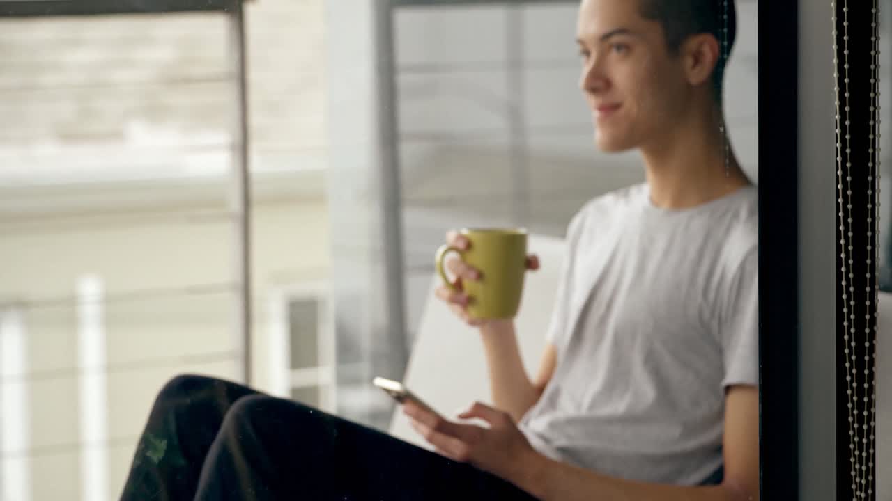 hombre usando teléfono móvil mientras toma café en casa 4k