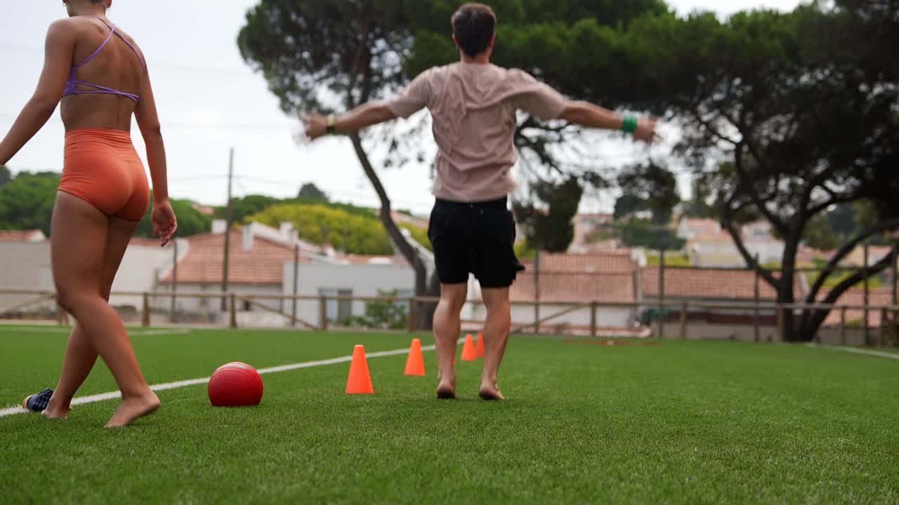 People training with a soccer ball and agility cones on a sports field